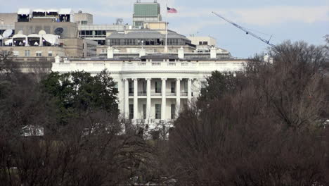 Una-Bandera-De-Estrellas-Y-Rayas-Ondeando-Sobre-La-Residencia-Presidencial-Oficial-De-La-Casa-Blanca-Se-Ve-A-Través-De-Un-Grupo-De-árboles.