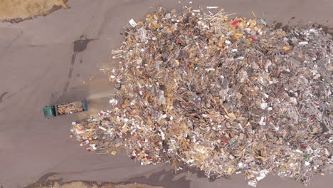 Huge-scrap-wood-pile-at-recycling-centre-as-truck-pulls-in-to-dump-more,-aerial