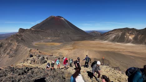 Vista-Panorámica-Del-Monte-Nga-Uruhoe-Mientras-Los-Excursionistas-Caminan-Por-Un-Sendero-Rocoso-En-La-Montaña-En-Tongariro-Apline-Crossing,-Nueva-Zelanda