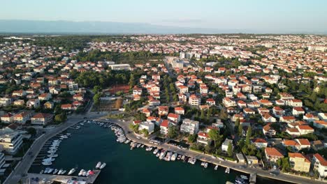 Red-rooftops-and-blue-sea,-small-boat-marina-and-distant-mountain