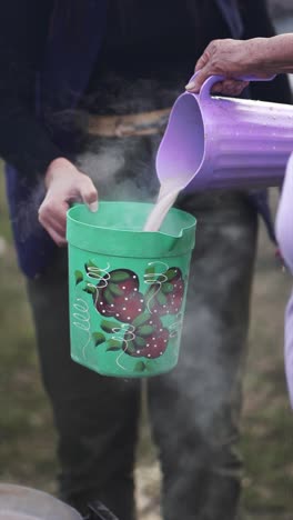 Boiling-chocolate-milk-is-poured-from-one-can-to-another-can-to-be-distributed-to-the-poor