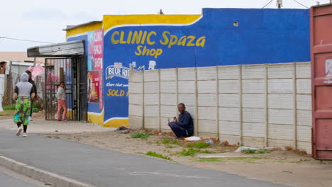 Drive-through-shanty-town-settlement-with-locals-walking-on-pavement