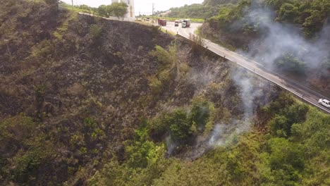 Vehicles-traveling-on-road-near-fire.-Aerial-rising