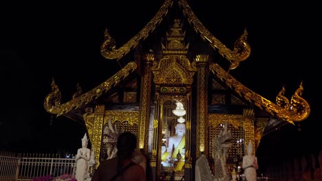 Lonely-woman-walking-towards-Buddhist-temple-at-night-in-Chiang-Mai,-Thailand