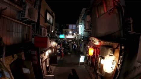 Wide-and-high-angle-footage-of-walking-through-the-famous-Golden-gai-bar-area-of-Shinjuku,-Tokyo,-at-night-with-tourists-walking-around