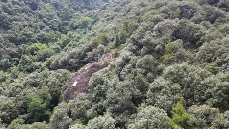 Children-in-a-summer-camp,-led-by-a-coach,-prepare-for-rope-descent-at-the-edge-of-a-cliff