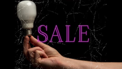 Holding-light-bulb,-hand-with-SALE-text-animation-over-black-background