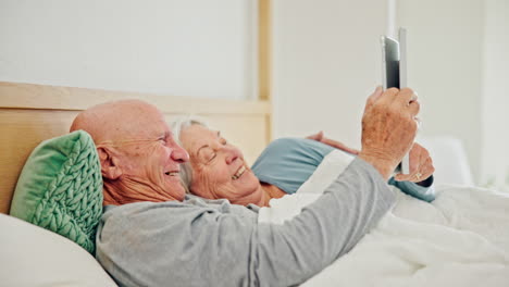 Senior-couple-lying-in-bed-with-tablet