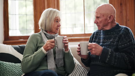 Love,-coffee-and-senior-couple-on-a-sofa-speaking