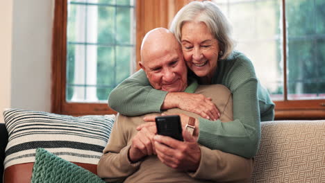 Senior-couple,-hug-and-relax-on-sofa-with-phone