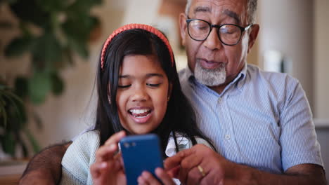 Child,-grandfather-and-cellphone-laugh-in-home