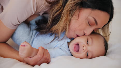 Happy,-kiss-and-baby-with-mom-in-bed-playing