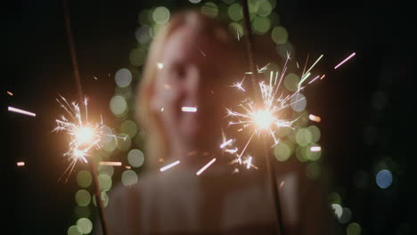 Happy-woman-holding-sparklers,-standing-against-the-backdrop-of-a-Christmas-tree-at-home.