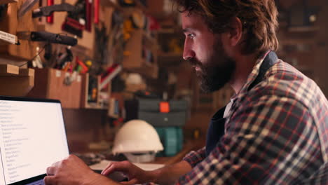 Man,-typing-and-carpenter-with-a-laptop