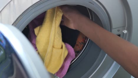 Man-putting-shirt-into-washing-machine