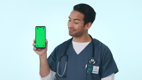 Asiatischer-Mann,-Arzt-Und-Zeigt-Auf-Das-Telefon-Auf-Grün