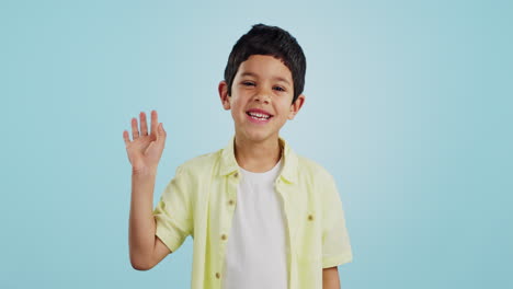 Kid,-hand-and-waving-with-smile-in-studio-on-blue