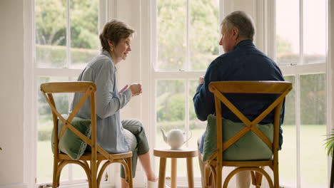 Old-couple-in-home,-tea-and-bonding-in-morning