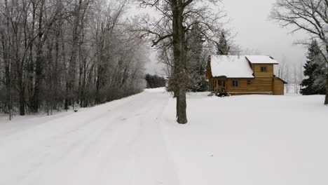 Slow-approach-to-a-beautiful-log-cabin-during-a-light-winter-snowfall