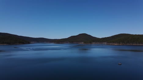 People-On-Boat-Floating-At-The-Calm-Blue-Waters-Of-Hinze-Dam---Blue-Sky-Over-The-Mountains-And-Advancetown-Lake---Gold-Coast,-QLD,-Australia