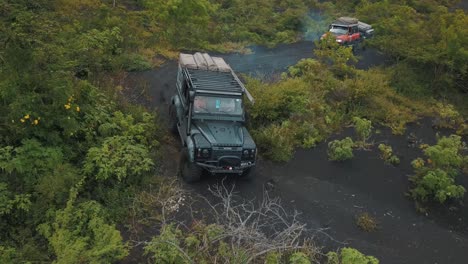Drone-aerial-flying-over-4x4-cars-driving-off-road-during-a-camping-trip-towards-pacaya-Bolcano-in-Guatemala,-Central-america