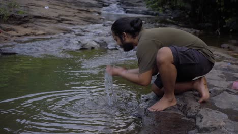 vivek-bearded-long-hair-man-washing-face-in-fresh-water-in-jungle