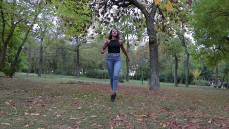 Girl-jumping-and-kicking-in-the-air-with-her-legs-in-a-park-in-autumn-in-slow-motion
