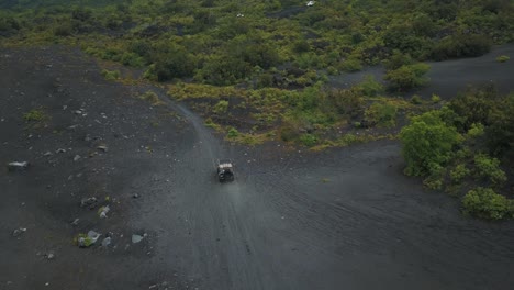 Drone-aerial-flying-towards-cars-driving-off-road-over-volcanic-sand-in-a-forest,-Pacaya-Volcano,-Guatemala,-Central-america
