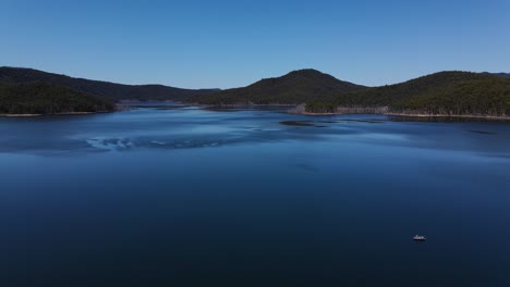 Stunning-Landscape-Of-Hinze-Dam-In-Summer---Serene-Waters-With-A-Lush-Mountains-In-The-Distance-Under-The-Bright-Blue-Sky---Gold-Coast,-QLD,-Australia