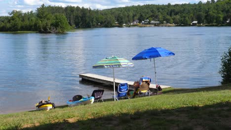 Chairs,-Umbrellas,-Kayaks-Near-the-Dock-and-Water---Relaxing-at-Cottage-Lake-House-Outdoors-in-Summer
