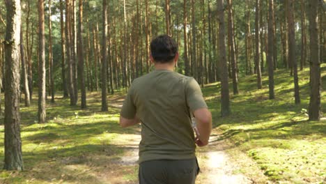 Young-Man-Running-In-The-Forest-Trail-Under-The-Shades-Of-Tall-Trees-Near-The-Arendel-Village-In-Zagorow,-Poland