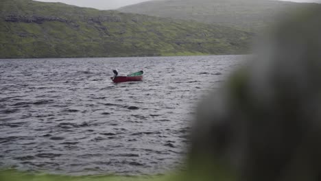 Slow-motion-shot-of-lonely-wooden-boat-on-lake-with-mountains-in-background