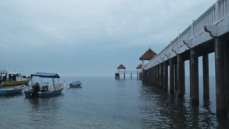 Wooden-footbridge-with-parking-boats-in-water-during-cloudy-day
