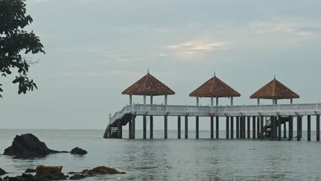 Friedliche-Weite-Aufnahme-Des-Ruhigen-Meeres-Mit-Holzsteg-Während-Des-Bewölkten-Tages-In-Malaysia,-Asien