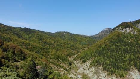 Mountains-covered-in-green-and-yellow-foliage-of-forest-on-both-sides-of-valley-in-Dardha,-Albania