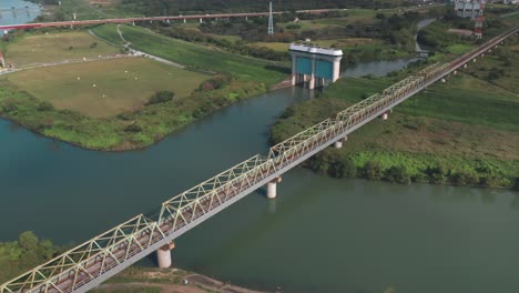 Zug-Fährt-An-Der-Eisenbahnbrücke-Mit-Dem-Schleusentor-In-Der-Ferne-Am-Fluss-Arakawa-In-Saitama,-Japan-Vorbei