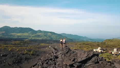 Drone-aerial-shot-of-two-travelers-observing-a-beautiful-landscape-near-camping-spot-in-Guatemala