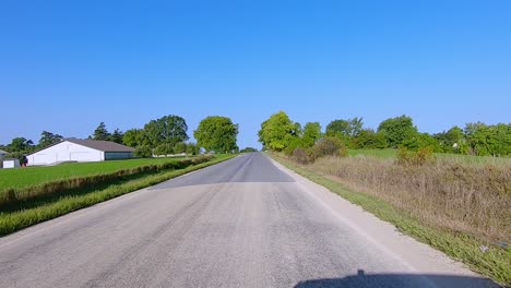 POV-while-driving-thru-rural-Iowa-on-a-paved-country-road-on-a-bright-sunny-summer-afternoon-in-Iowa
