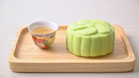 Chinese-moon-cake-green-tea-flavour-with-tea-on-wood-plate