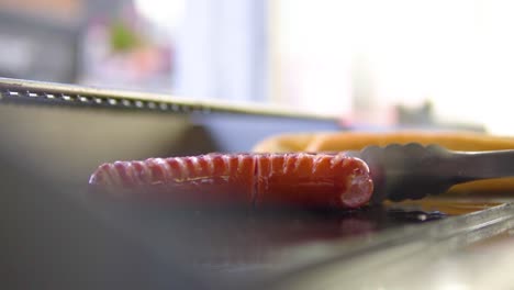 Slightly-moving-hotdogs-on-grill-in-windowed-fast-food-close-up-slowmotion