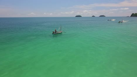 Aerial-forward-dolly-shot-of-a-traditional-shrimp-fisherman-on-small-wooden-boats-in-Thailand-with-small-islands-in-the-background