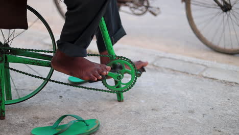 Closeup-barefoot-adult-male-pedals-makeshift-mobile-bicycle-with-chain