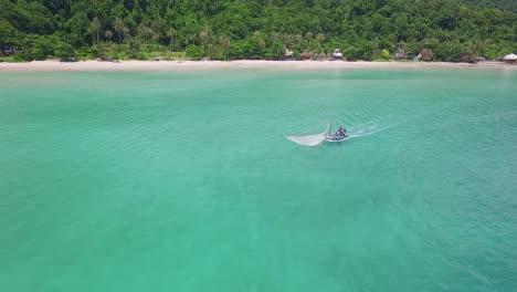 Aerial-backwards-dolly-shot-of-a-traditional-shrimp-fisherman-on-small-wooden-boat-in-Thailand-with-a-beach-in-the-background