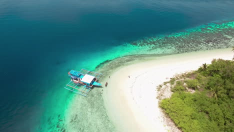 Orbit-Aerial-Shot-Of-A-Passenger-Boat-Docked-In-A-Beautiful-White-Beach-Island-In-Palawan