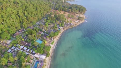 Tropical-Island-drone-dolly-shot-of-Thailand-island-beach-resorts-with-lush-green-rain-forest-and-tropical-palm-trees-with-white-sand-beach-and-rocky-coastline