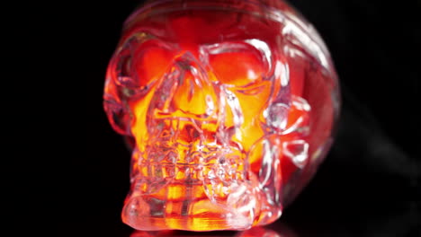 Close-up-of-glowing-orange-glass-skull-at-halloween,-slow-zoom-out