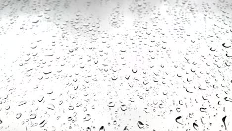 Relaxing-droplets-of-rain-falling-on-a-large-window-with-a-cloudy-white-sky-in-the-background-during-lockdown