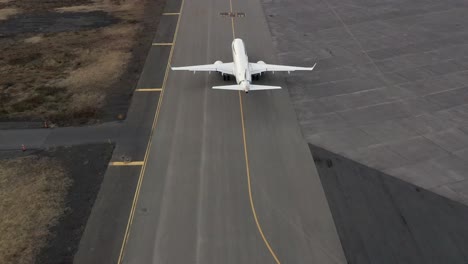 Aerial-of-business-jet-driving-on-tarmac-on-tricycle-landing-gear-towards-runway