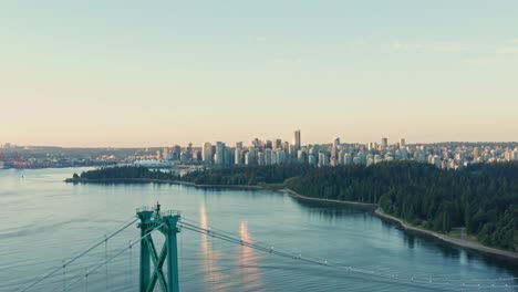 Unglaubliche-Aufnahme,-Die-An-Der-Lions-Gate-Bridge-Herunterfliegt,-Wobei-Das-Licht-Während-Des-Sonnenuntergangs-Auf-Wolkenkratzern-Und-Dem-Hafen-Von-Vancouver-Reflektiert-Wird