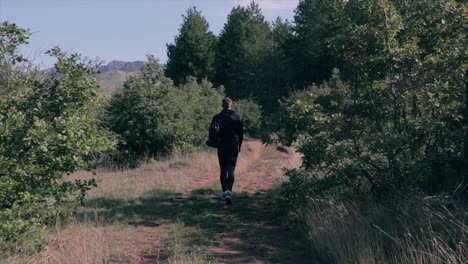 Man-walking-through-a-forest-path